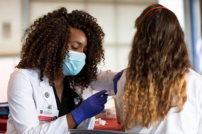 A university health care worker administering a vaccination.